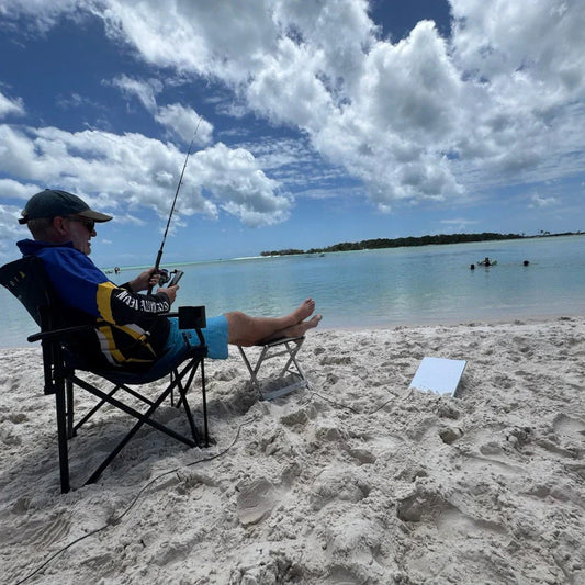 Traveller fishing on the beach running Starlink on 12V for off-grid internet access