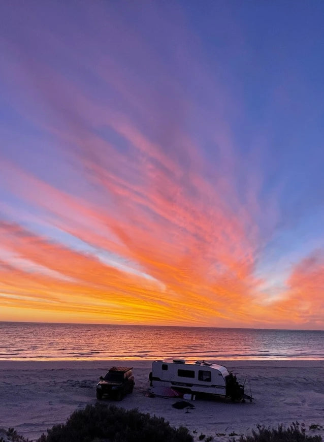 Campalot 4WD and caravan set up on a beach at sunset, showcasing off-grid camping and coastal adventure