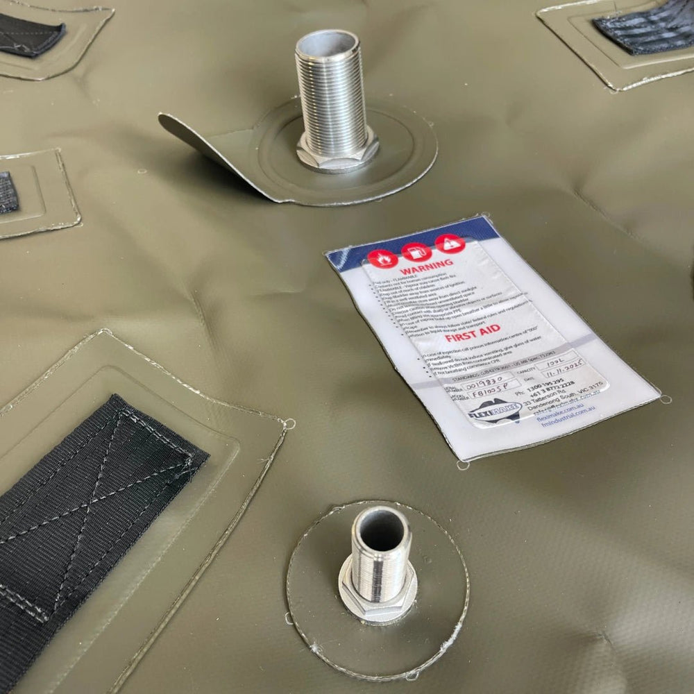 Close-up of Fleximake fuel bladder showing stainless steel inlet and outlet fittings with reinforced mounting points